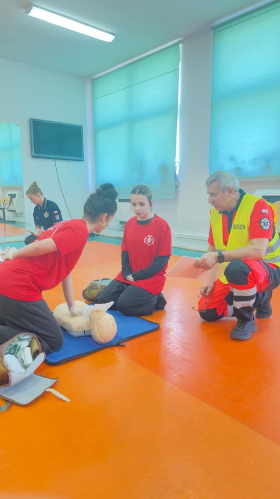 zdjęcie dwóch wolontariuszy sędziowów i uczestniczki na Powiatowych Mistrzostwach Pierwszej Pomocy w Lubaniu
