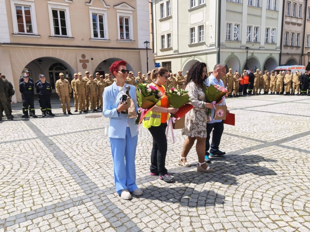 XL Medyczne Manewry Straży Pożarnej w Jeleniej Górze, na zdjęciu na Placu Ratuszowym reprezentacja Pogotowia Ratunkowego trzech ratowników medycznych oraz główna księgowa odbierająca kwiaty
